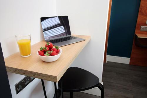 una mesa con un tazón de fresas y un vaso de zumo de naranja en Boutique one bedroom apartment in Cardiff, en Cardiff