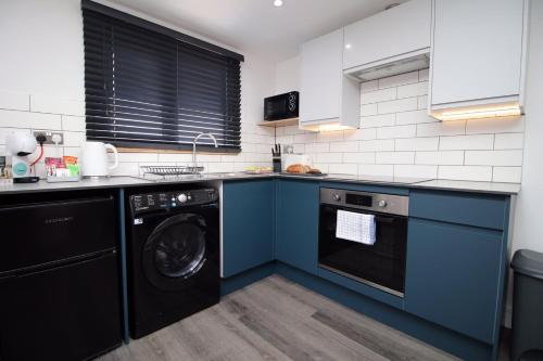 Boutique one bedroom apartment in Cardiff في كارديف: مطبخ مع دواليب زرقاء وغسالة صحون