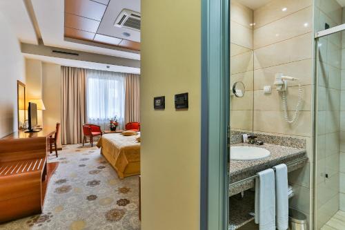 a hotel room with a bathroom with a bed and a sink at Kings Park Hotel in Podgorica