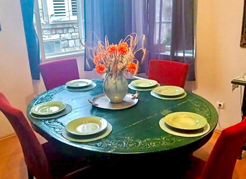 una mesa con platos y un jarrón con flores. en Large Three Bedroom, Center of Old Town en Dubrovnik