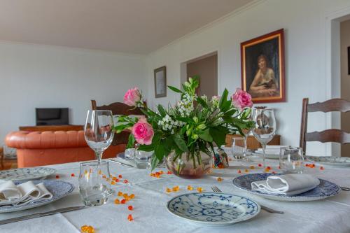 une table à manger avec des fleurs roses dans un vase dans l'établissement Chez Maryse et Guy - Bel Appt pour 4 avec jardin, à La Ville-aux-Clercs