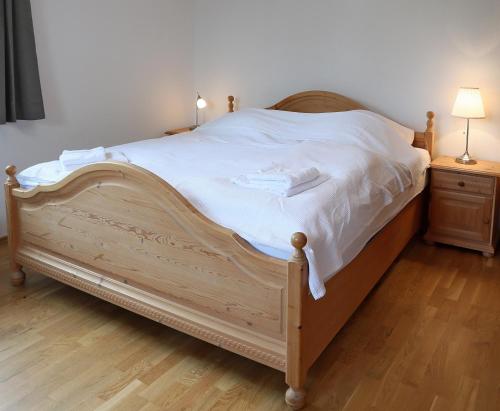 a bedroom with a wooden bed with white sheets at 90m² Top Holiday Home Upper Bavaria + Munich South in Schäftlarn