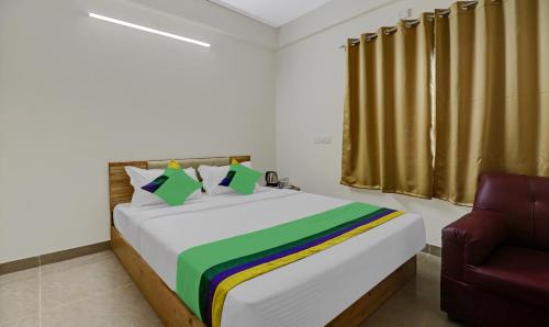 a bedroom with a large bed and a chair at Treebo Trend SLN Heritage in Bangalore