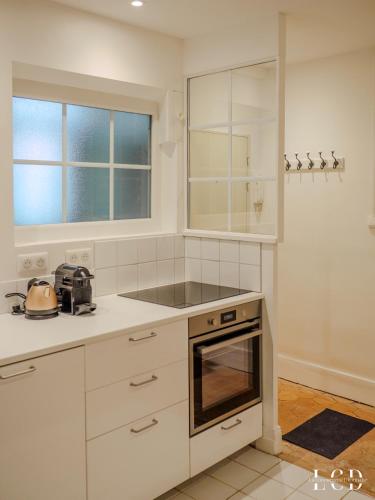 une cuisine avec des armoires blanches et un four à plaques de cuisson dans l'établissement Le Berbisey Dijon Centre, à Dijon