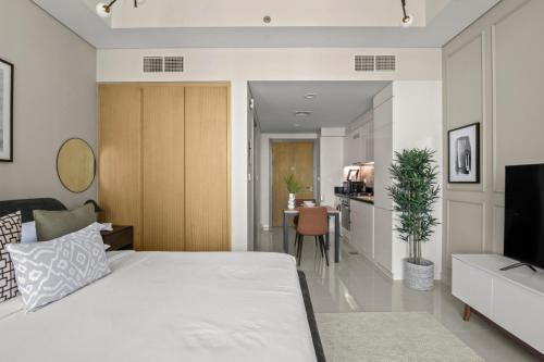Cet appartement comprend une chambre avec un grand lit blanc et une cuisine. dans l'établissement GuestReady - Contemporary studio in Business Bay, à Dubaï