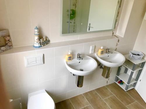ein Badezimmer mit zwei Waschbecken, einem WC und einem Spiegel in der Unterkunft Abelia Ferienwohnung GröF in Helmstedt