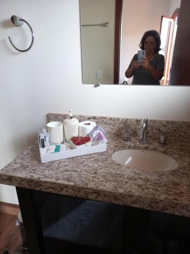 a woman taking a picture of a sink in a bathroom at Hospedagem Aconchegante in Espirito Santo Do Pinhal