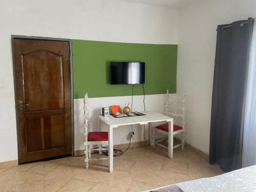 Habitación con escritorio y TV en una pared verde. en Bruks Guest House en Kumasi
