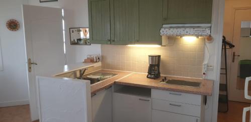 a kitchen with white cabinets and a counter top at Appartement front de mer vue mer 3 personnes + 1 bebe in Hermanville-sur-Mer