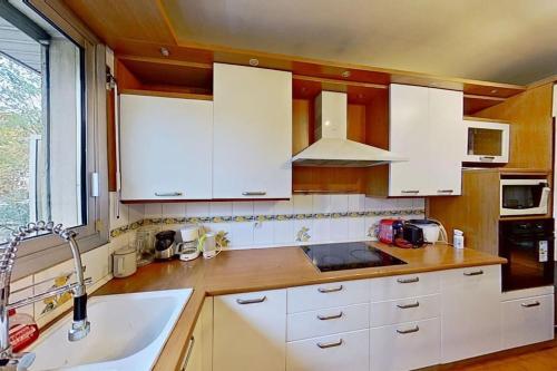 une cuisine avec des armoires blanches et un évier dans l'établissement Appartement grand luxe 180m2, à Neuilly-sur-Seine