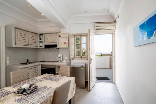 Angel Santorini Residences في Vourvoúlos: مطبخ مع دواليب بيضاء وطاولة في الغرفة