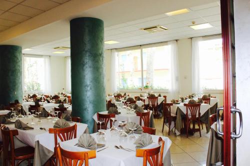 a dining room with tables and chairs and windows at Blue Loft Hotel in Cesenatico