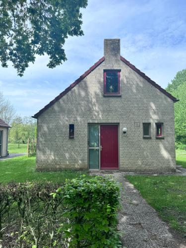 a brick house with a red door at Villa vakantiehuis in Ewijk