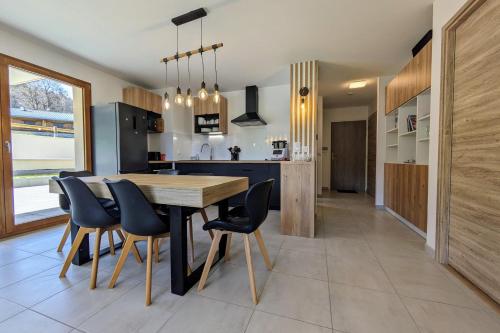 a kitchen and dining room with a wooden table and chairs at Spacieux appartement au pied des pistes in La Féclaz