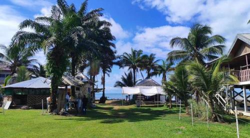 Un groupe de personnes debout sous les palmiers près de l'océan dans l'établissement Kribi Trip Experience, à Kribi