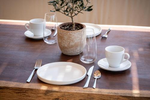 a wooden table with plates and cups and a potted plant at Foneas Bay Villa in Proástion