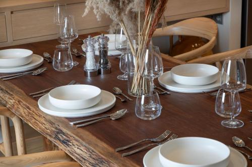 a wooden table with white plates and glasses on it at Foneas Bay Villa in Proástion