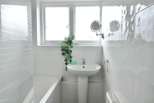 a white bathroom with a sink and a window at 5 Bed Luxury London Home in London