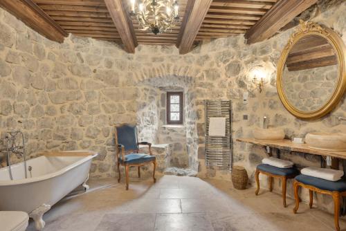 Baño de piedra con bañera y espejo en Château de Saint Vidal en Saint-Vidal