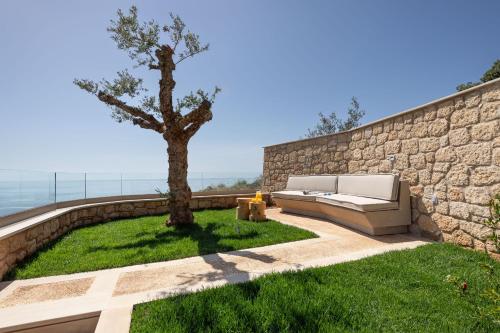 a retaining wall with a couch next to a tree at Foneas Bay Villa in Proástion