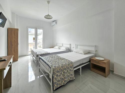 Habitación blanca con 2 camas y mesa en Exarhos Apartment, en Paralia Katerinis