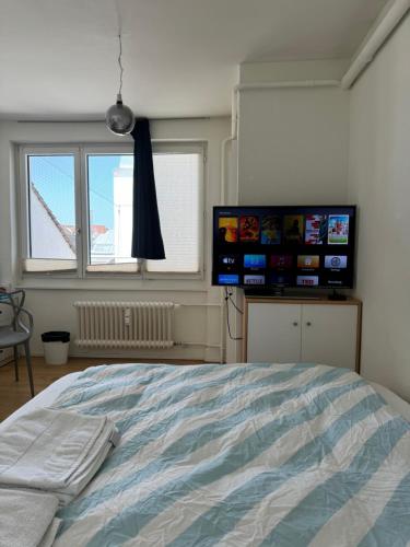 1 dormitorio con 1 cama y 2 TV en la pared en City Center Studio-balcony at town hall en Basilea