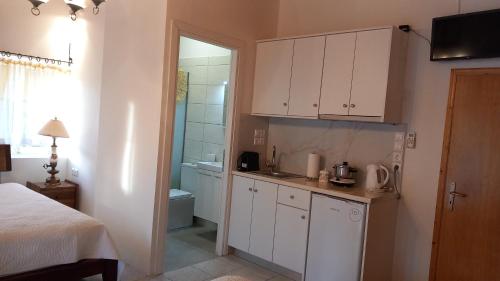 una pequeña cocina con armarios blancos en un dormitorio en Kassi's House, en Marantochori