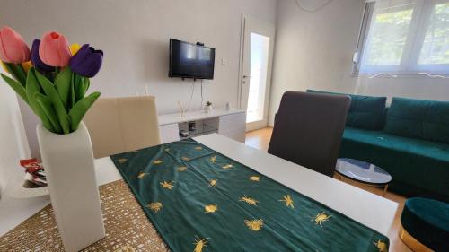 a living room with a table with flowers in a vase at Apartman SunShine in Trebinje