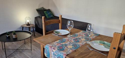 - une salle à manger avec une table, des chaises et des verres à vin dans l'établissement Le petit Jungle - hyper centre, à Mont-de-Marsan