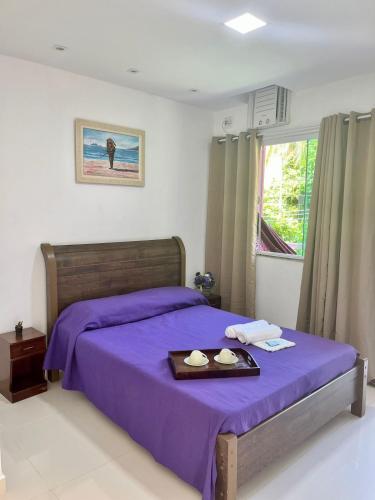 a bedroom with a purple bed with a tray of food at Flat Três Praias in Angra dos Reis
