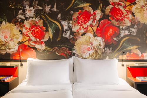 a bedroom with a painting of flowers on the wall at Leonardo Hotel Den Haag Babylon in The Hague
