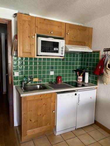 une cuisine avec un évier et un micro-ondes dans l'établissement 2 pièces La Clusaz Centre village dans petite résidence, à La Clusaz