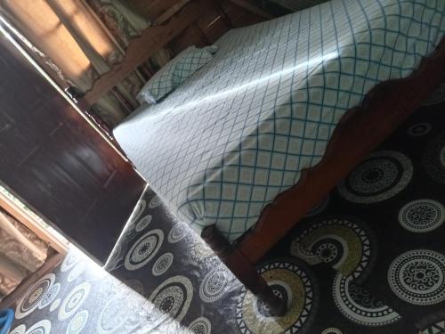 a bed with a checkered sheet on it next to a floor at Hostal claire in El Quije