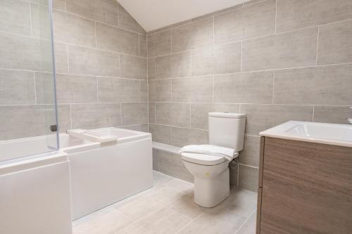 a bathroom with a toilet and a tub and a sink at Beautifully done 5 bed barn conversion in Heswall - Sleeps up to 10 in Heswall