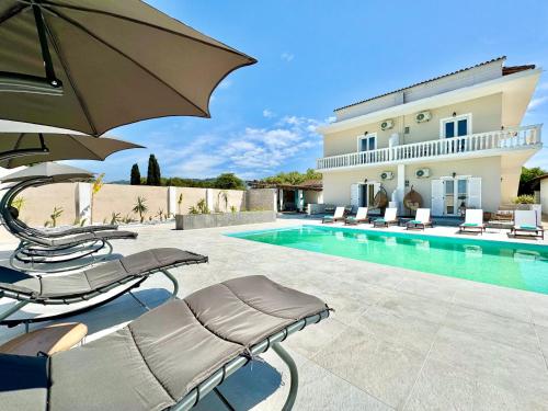 a swimming pool with chairs and an umbrella next to a house at Villa Doma with private pool for up to 29 guests by DadoVillas in Roda