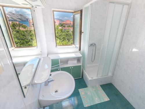 a bathroom with a sink and a toilet and two windows at Apartment and rooms Kristina in Baška
