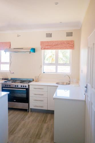 a kitchen with white cabinets and a stove and a window at 36 Alexander Guesthouse,Highlands,Harare in Highlands
