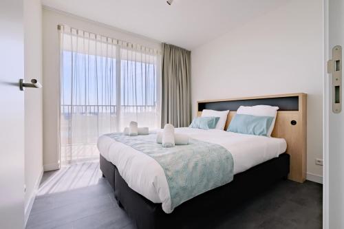 a bedroom with a large bed with a large window at Dormio Breskens Apartments & Penthouses in Breskens