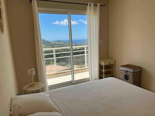 a bedroom with a bed and a large window at Casa Antonietta Alata vue imprenable sur la mer in Alata