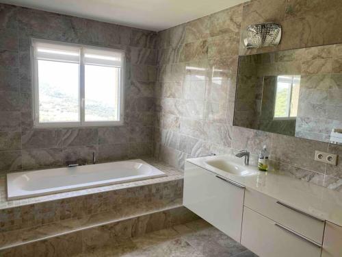 a bathroom with a tub and a sink and a mirror at Casa Antonietta Alata vue imprenable sur la mer in Alata