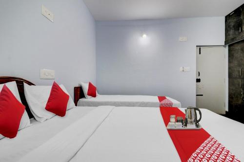 1 dormitorio con 2 camas y almohadas rojas y blancas en Flagship Sai International Near Nagasandra Metro Station en Bangalore