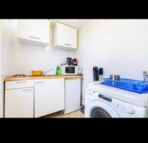une cuisine avec un lave-linge et un micro-ondes dans l'établissement Appart Paris vue Tour Eiffel, à Paris