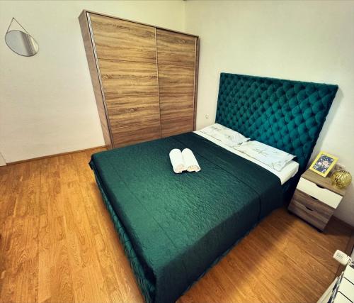 a bedroom with a green bed with slippers on it at Apartman SunShine in Trebinje