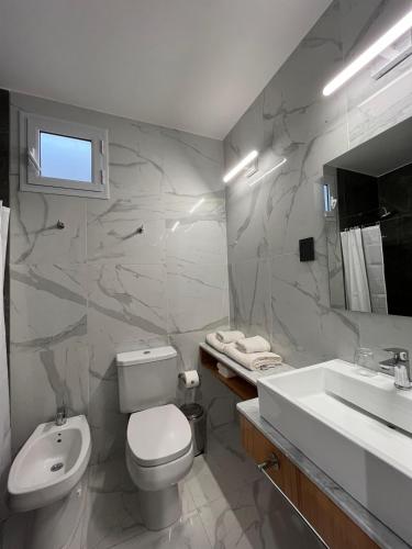 a bathroom with a white toilet and a sink at TERMAS PISMANTA Hotel & Spa in Las Flores