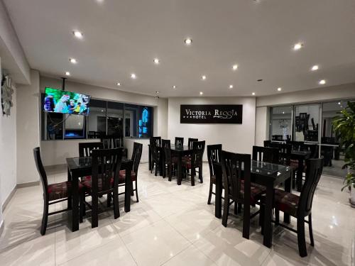 un restaurante con mesas y sillas negras y TV en Hotel Reggia en Tacna