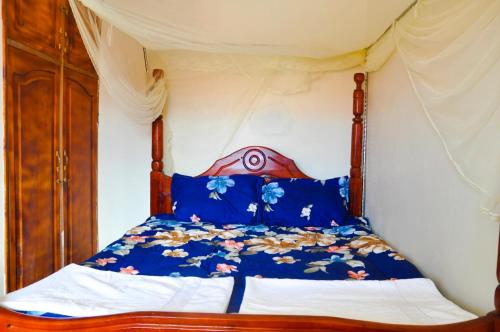 1 cama con edredón azul y almohadas azules en Kabale town flat (sitting and bedroom), en Kabale
