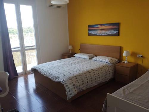 a bedroom with a bed and a yellow wall at Casa ANNA, casa tua in Le Grazie