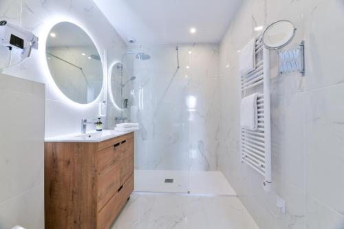 a white bathroom with a sink and a mirror at Logis Hotel & Restaurant Bergeret Sport in Hendaye