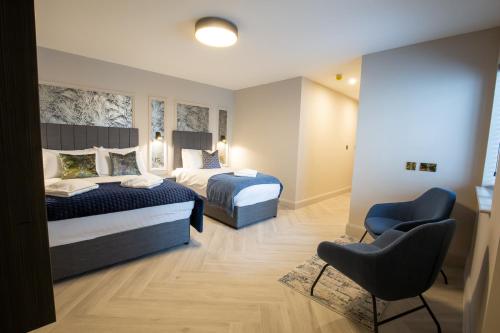 a bedroom with two beds and a chair at The Abbeygate Townhouse in Galway