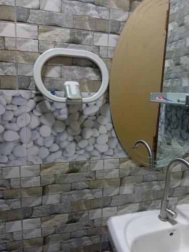 y baño con lavabo y espejo circular grande. en Casa Linda en Maputo